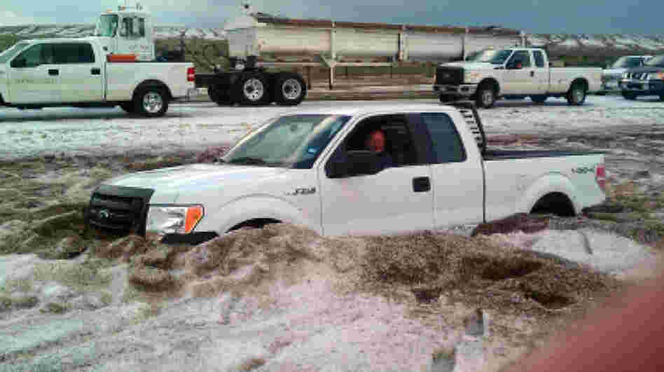 In this photo taken Wednesday and provided by the Amarillo/Potter/Randall Office of Emergency Management a motorist sits in a truck partially buried in slushy hail near Amarillo, Texas. 