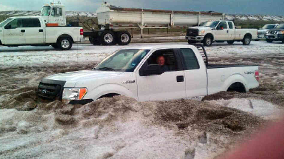 In this photo taken Wednesday and provided by the Amarillo/Potter/Randall Office of Emergency Management a motorist sits in a truck partially buried in slushy hail near Amarillo, Texas. 
