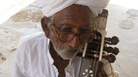 Sakar Khan with his kamancha in his home in Hamira, Jaisalmer, Rajasthan. He's passed his favorite kamancha — the one he got from his father — to his son, Darra. But this one plays just fine, if he's the guy playing it. Sakar Khan with his kamancha in his home in Hamira, Jaisalmer, Rajasthan. He's passed his favorite kamancha — the one he got from his father — to his son, Darra. But this one plays just fine, if he's the guy playing it.