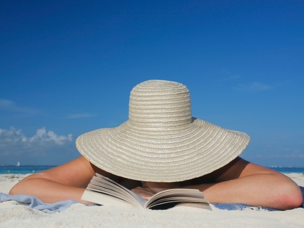 A woman reads on the beach. 