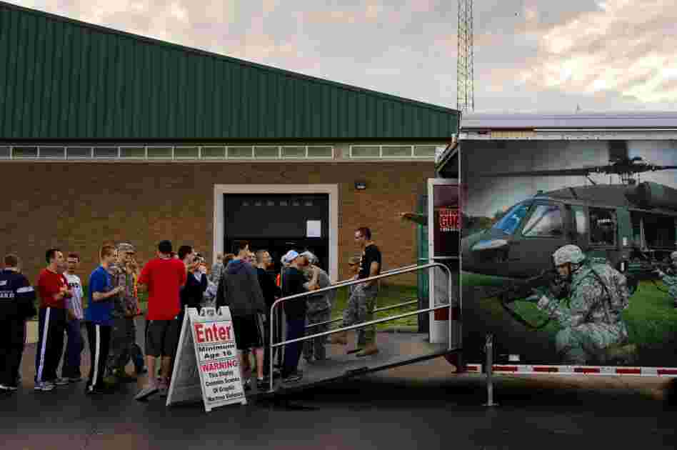 Army recruits form a line outside an Army National Guard trailer where they can watch films depicting combat.