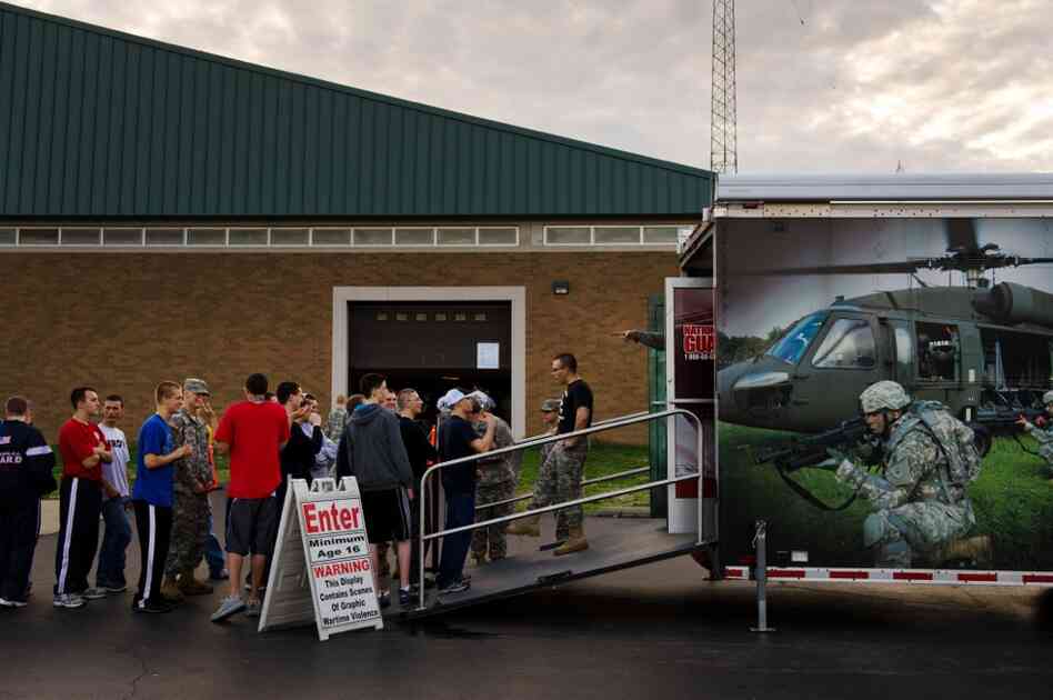 Army recruits form a line outside an Army National Guard trailer where they can watch films depicting combat.