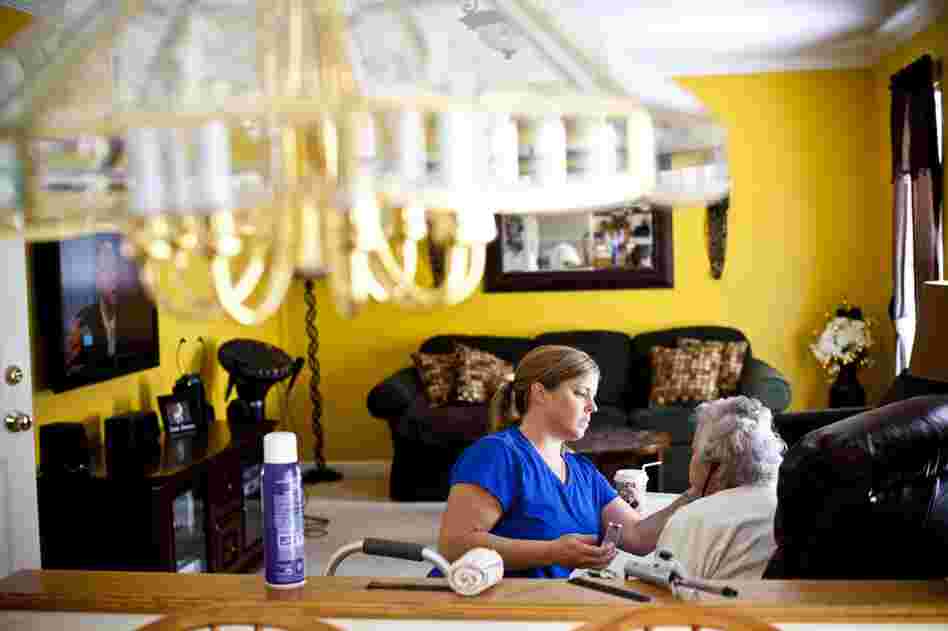 LaDonna Martin applies makeup to AnnaBelle in her family's living room. Her limited mobility prevents her from doing daily activities independently.