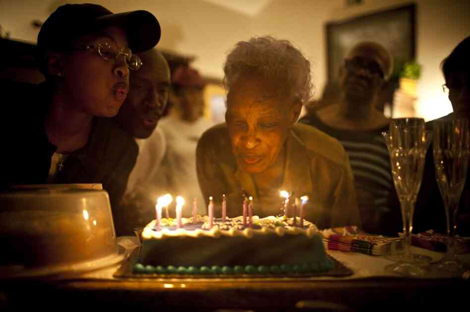 Ida Christian, who suffers from dementia, gets help from her granddaughter, Yolanda Hunter (left), in blowing out the candles on her birthday cake. Yolanda quit her lucrative job to become Ida's full-time caregiver.