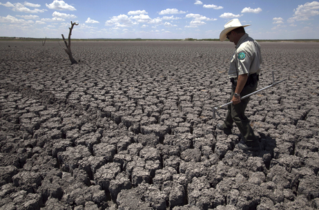 In this Aug 3, 2011 file photo, Texas State Park police officer Thomas Bigham walks across the cracked lake bed of O.C. Fisher Lake, in San Angelo, Texas. In this Aug 3, 2011 file photo, Texas State Park police officer Thomas Bigham walks across the cracked lake bed of O.C. Fisher Lake, in San Angelo, Texas.