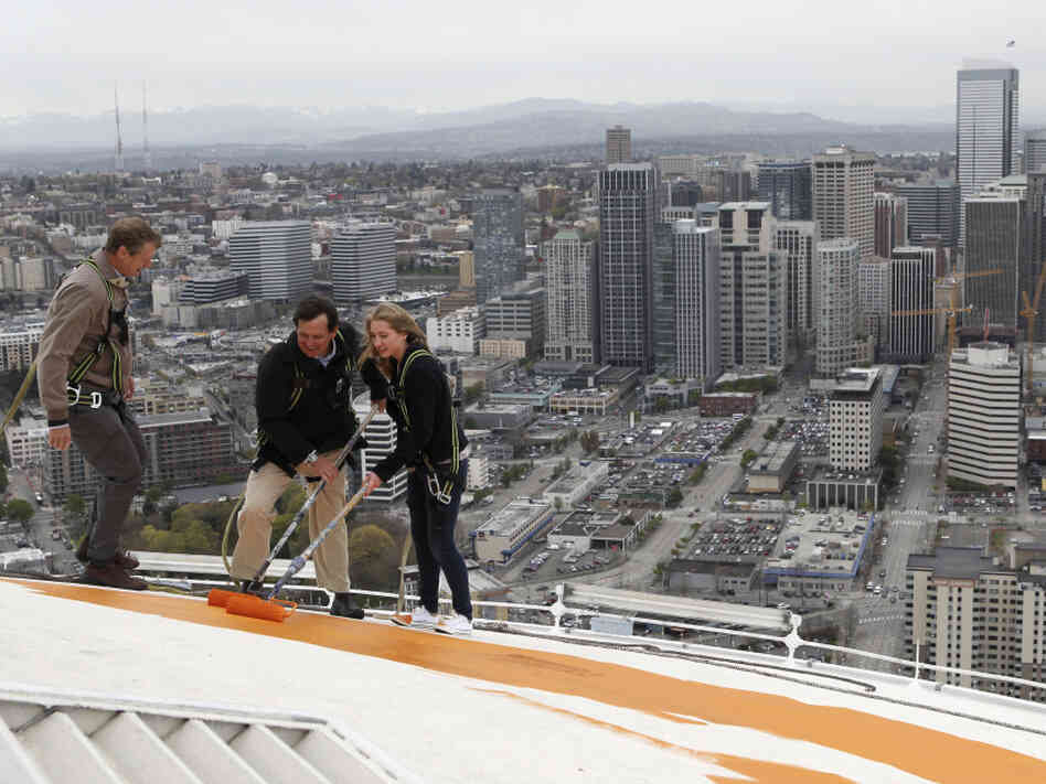 Jeff Wright (center), whose family owns the Space Needle, starts the repainting of the iconic structure on Tuesday with his 15-year-old daughter, Mauren, and Space Needle board member Stuart Rolfe. The new color is the original color, dubbed "galaxy gold."