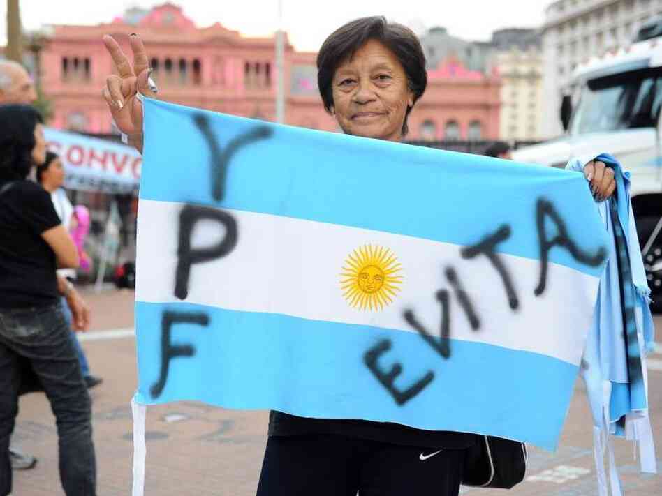A woman holds an Argentine national flag in front of the presidential palace. A woman holds an Argentine national flag in front of the presidential palace.