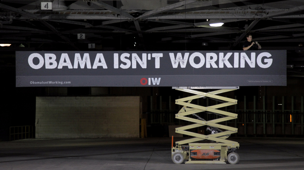 A campaign worker hangs a sign at a campaign stop for Republican presidential candidate Mitt Romney in Lorain, Ohio, on Thursday.