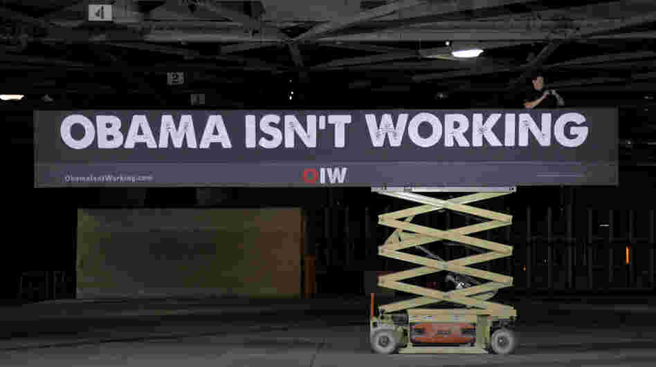 A campaign worker hangs a sign at a campaign stop for Republican presidential candidate Mitt Romney in Lorain, Ohio, on Thursday.
