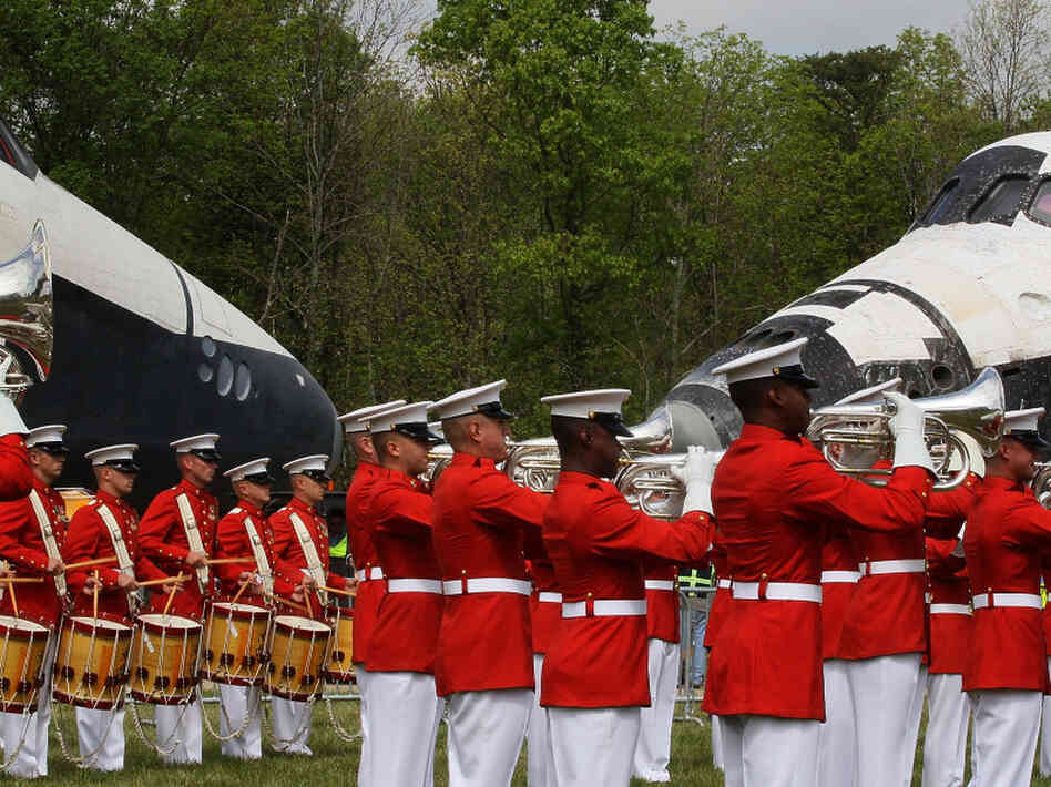 A military band plays as the Space Shuttle Discovery (R), and the Space Shuttle Enterprise (L), sit nose to nose, during an event at the Smithsonian National Air and Space Museum Steven F. Udvar-Hazy Center April 19, 2012 in Chantilly, Virginia.