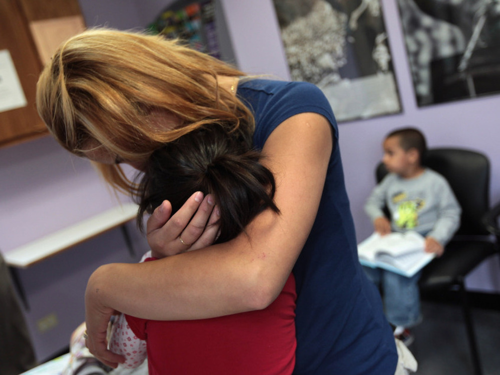 Many working mothers say their employers don't support them when they need to tend to a sick child. In this file photo, a single mother holds her child at a health clinic in Colorado.