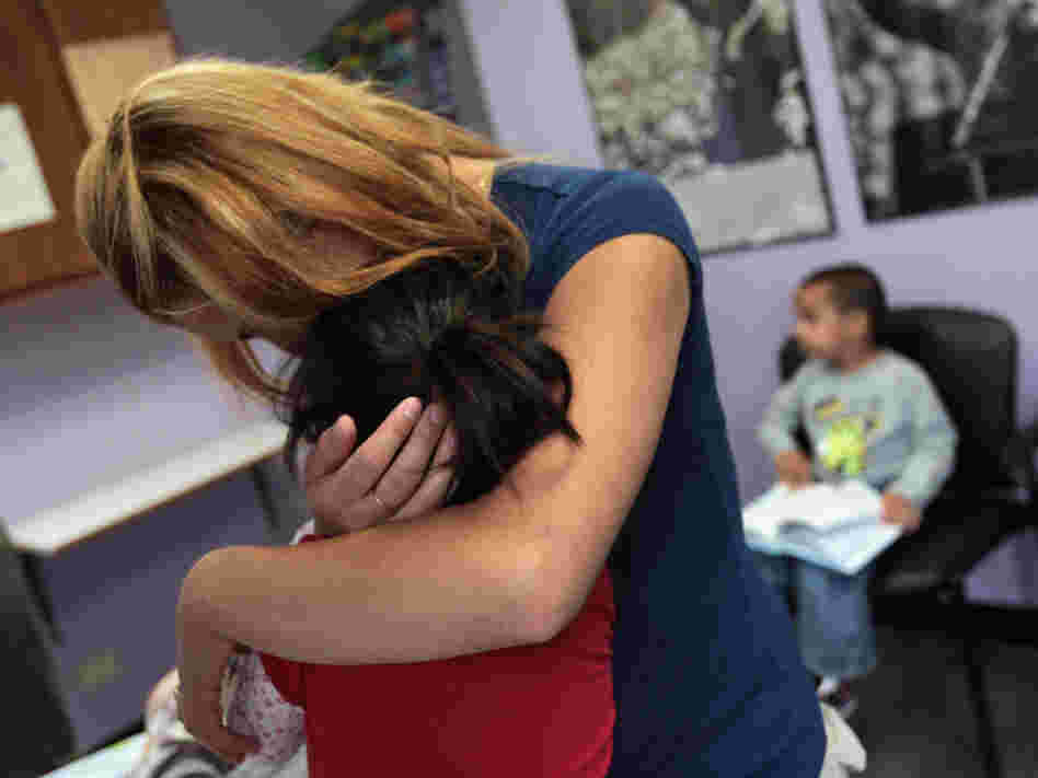 Many working mothers say their employers don't support them when they need to tend to a sick child. In this file photo, a single mother holds her child at a health clinic in Colorado.