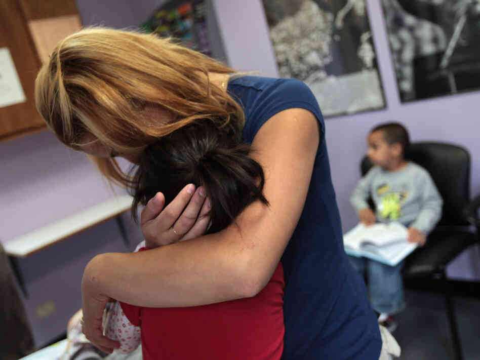 Many working mothers say their employers don't support them when they need to tend to a sick child. In this file photo, a single mother holds her child at a health clinic in Colorado.