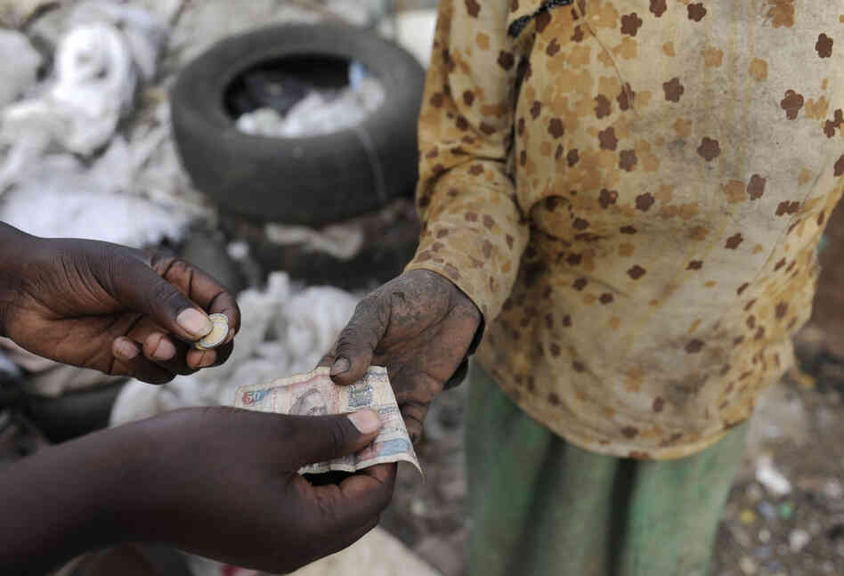 A woman gets paid after sifting through a mound of garbage at the main dumpsite in Nairobi, Kenya. 
