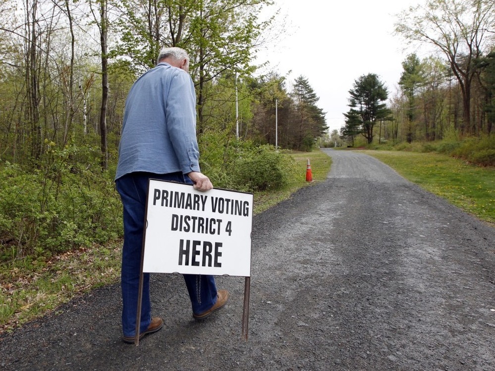 A man prepares to put in place an informational sign for voters on primary day 2012 in North Greenbush, N.Y.