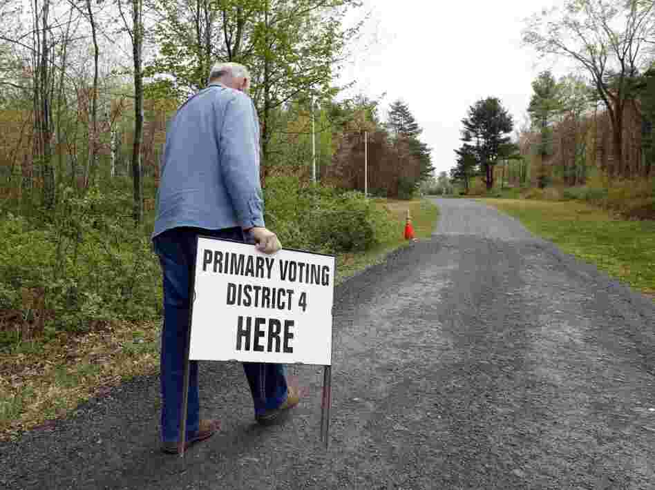 A man prepares to put in place an informational sign for voters on primary day 2012 in North Greenbush, N.Y.