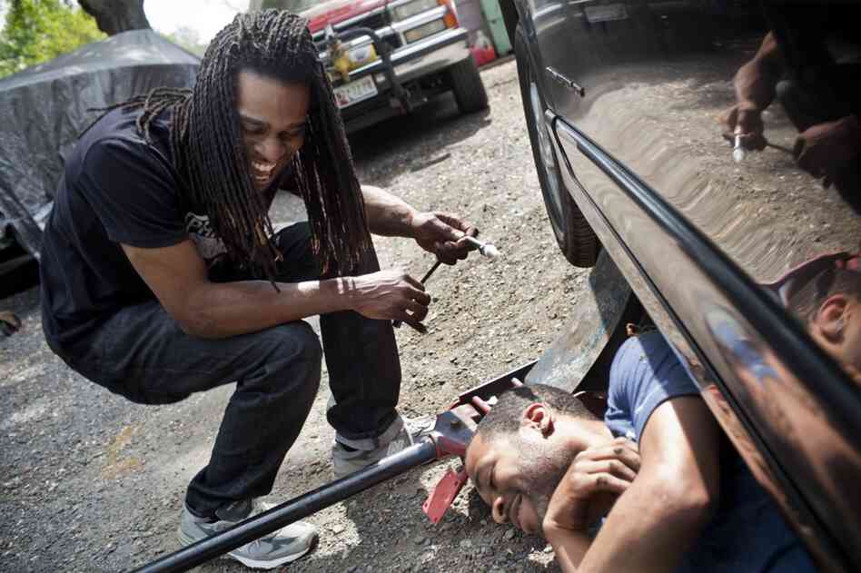Nicholas (left) laughs with his childhood friend Corey Buford while they work on Nicholas' car. Nicholas has briefly abandoned his music aspirations and is close to getting a job with Comcast to install cable. "The money is more important," Nicholas says. "I need something that I can contribute [to the household] with."