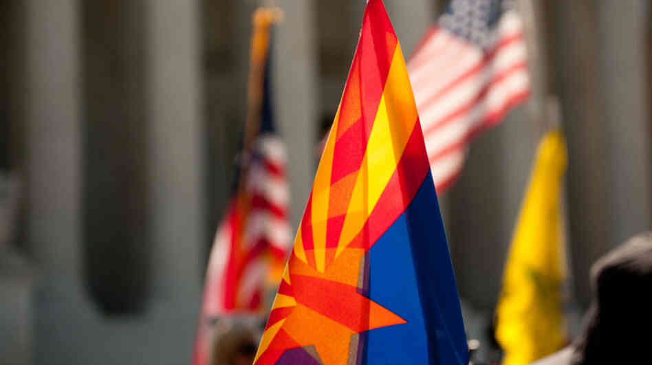Supporters of Arizona's immigration law fly the flags of the state (center), the United States and the Tea Party on the steps of the Supreme Court during oral arguments about the law on Wednesday.