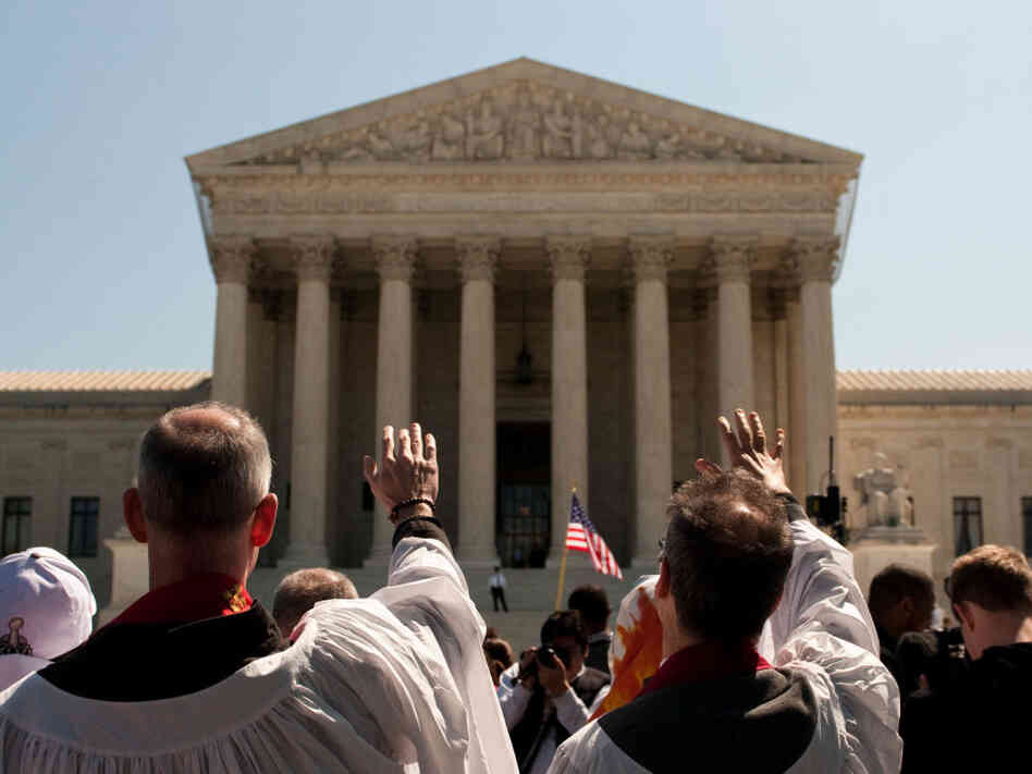 A group dressed in robes parades in silence around the Supreme Court building in a Bible-inspired "Jericho Walk."