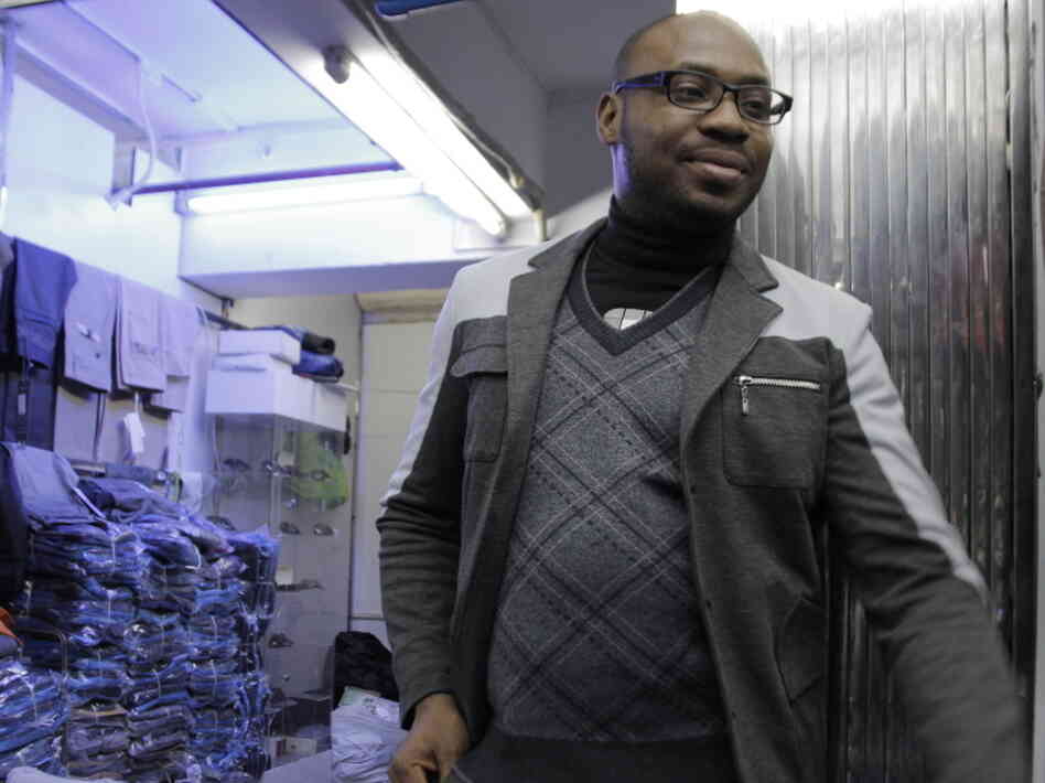 A trader who goes by the name Fortunato — he says it's his "designer name" — stands outside one of the clothing shops in the Little Africa section of Guangzhou. He's been living in the Chinese city for five years.