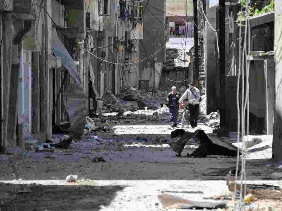 Syrians walk in an alley damaged by Syrian army shelling in the Bab Sbaa neighborhood in Homs province, central Syria, on April 21.