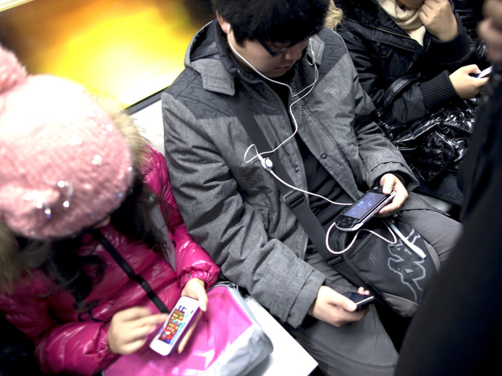 Commuters immersed in their smartphones ride the subway in Beijing.
