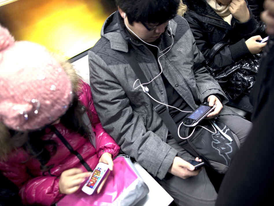 Commuters immersed in their smartphones ride the subway in Beijing.