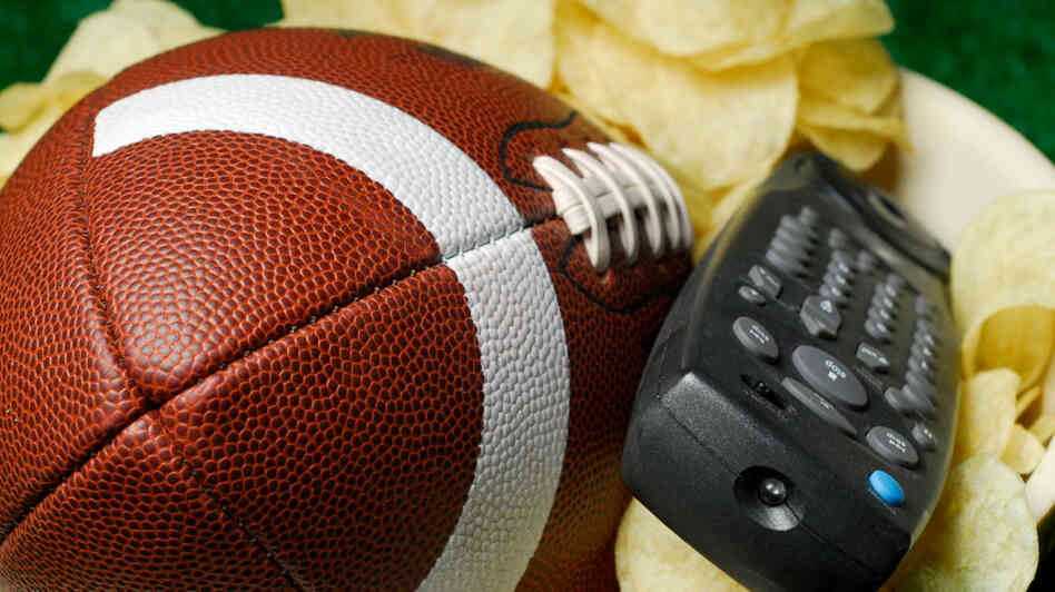 A football and a television remote sit expectantly in a bowl of chips, waiting for an NFL Draft fan to claim them.