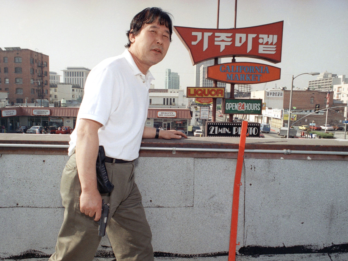 Richard Rhee stands vigil, armed with a handgun and a cellphone, on the roof of his grocery store in the Koreatown area of Los Angeles on May 2, 1992. A disproportionate number of Korean businesses were looted and gutted by fires in the L.A. riots.