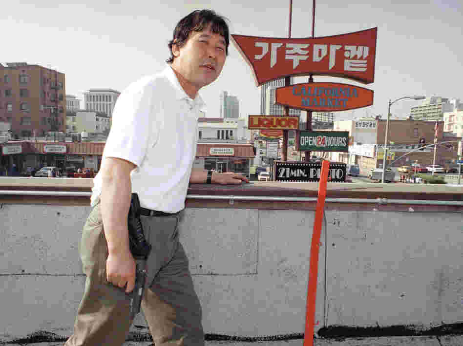 Richard Rhee stands vigil, armed with a handgun and a cellphone, on the roof of his grocery store in the Koreatown area of Los Angeles on May 2, 1992. A disproportionate number of Korean businesses were looted and gutted by fires in the L.A. riots.