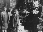 John D. Rockefeller handing out Christmas presents to a group of children. John D. Rockefeller handing out Christmas presents to a group of children.
