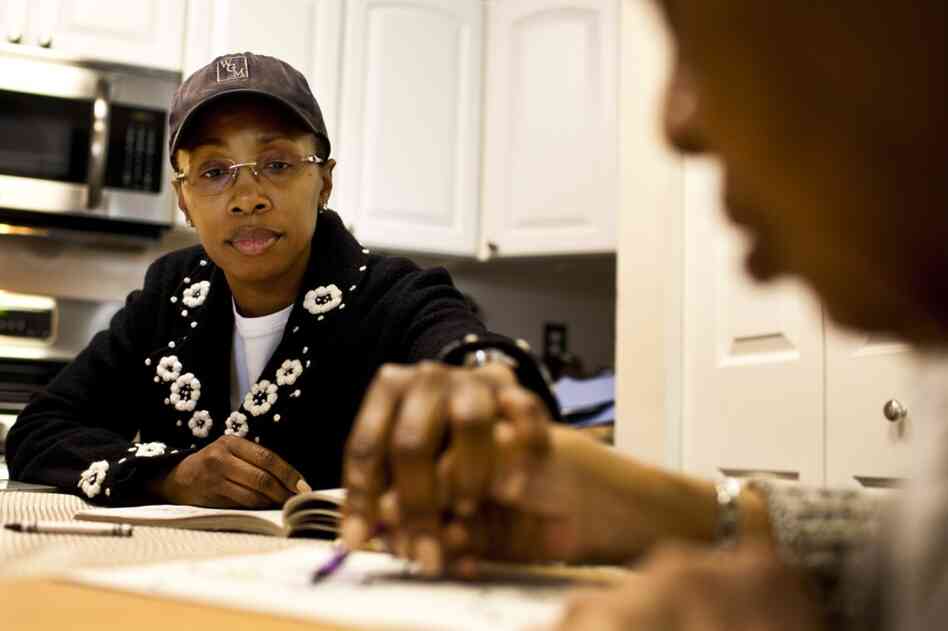 Yolanda, 43, helps Ida color at the family's kitchen table. She has been taking care of her grandmother daily for over two years and insists it is the best care for Ida.