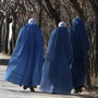 Afghan women pass U.S. soldiers near Bagram Air Base outside Kabul in 2010. While conditions for Afghan women have improved over the past decade, but they still face many restrictions, as well as abuses like honor killings.