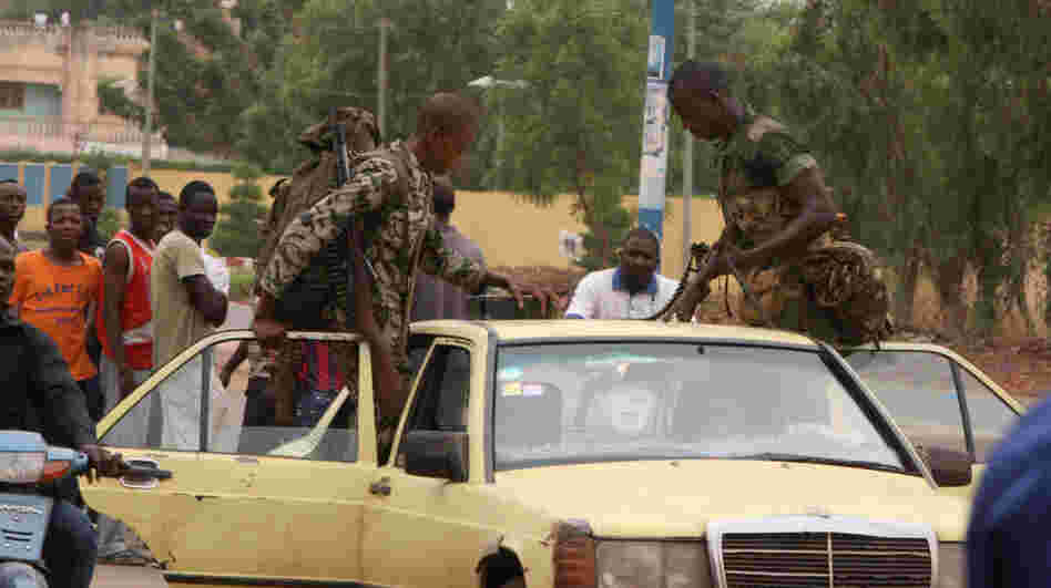 Soldiers loyal to junta leaders in Mali load their weapons, including a machine gun, onto a taxi after leaving a military camp where anti-junta forces were subdued.