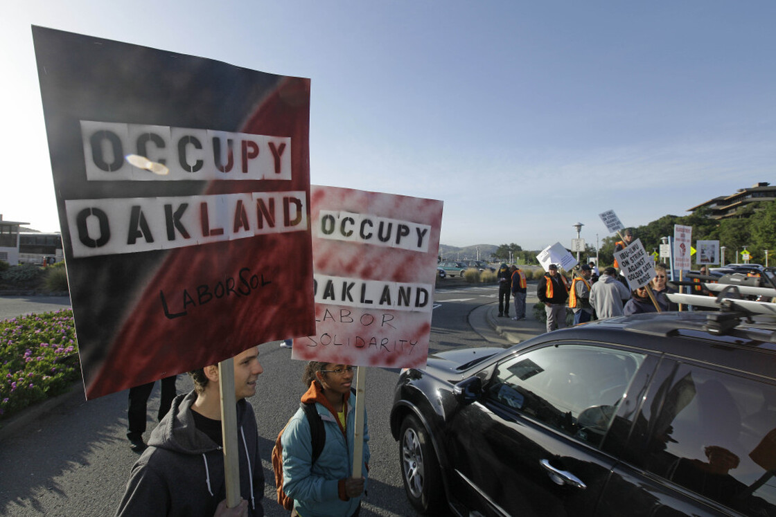 Two members of Occupy Oakland join striking Golden Gate Bridge, bus and ferry workers at the Larkspur Ferry Terminal in Larkspur, Calif on Tuesday.