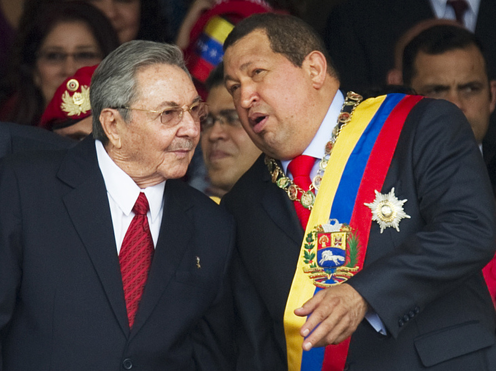 Venezuelan President Hugo Chavez (right) speaks with his Cuban counterpart, Raul Castro, during a military parade earlier this year in Caracas, Venezuela. Chavez has provided an economic lifeline to Cuba. Now, that lifeline is under threat as the Venezuelan leader fights cancer and faces re-election.