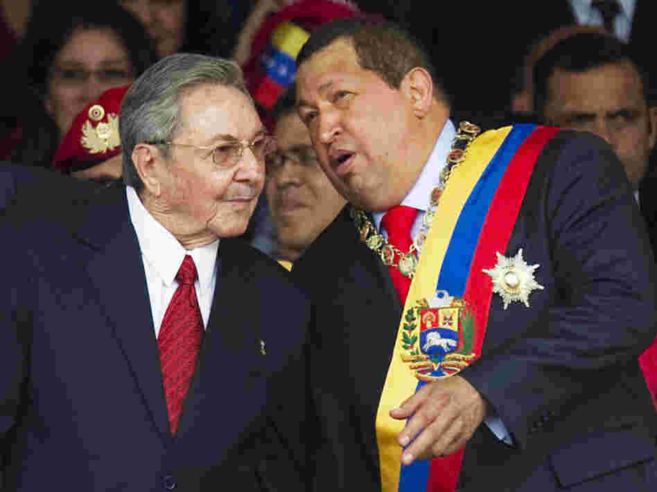Venezuelan President Hugo Chavez (right) speaks with his Cuban counterpart, Raul Castro, during a military parade earlier this year in Caracas, Venezuela. Chavez has provided an economic lifeline to Cuba. Now, that lifeline is under threat as the Venezuelan leader fights cancer and faces re-election.