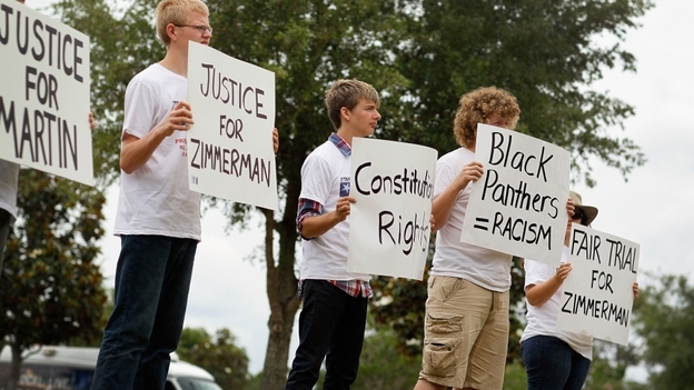 People hold signs during a small April rally in Sanford, Fla., that was billed as an opportunity to show support for the constitutional rights of George Zimmerman and Trayvon Martin.