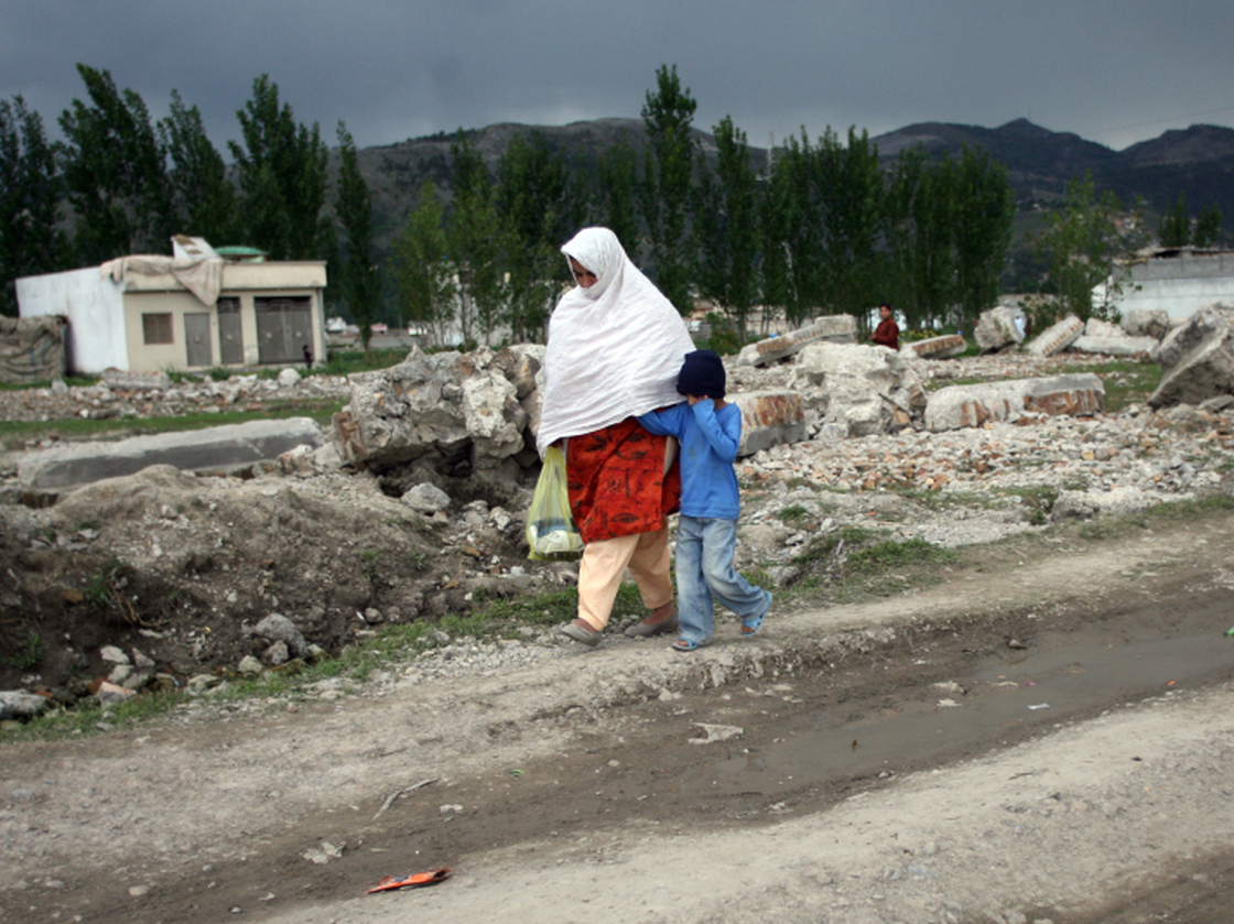 Pakistanis walk past the rubble of bin Laden's demolished compound this week.