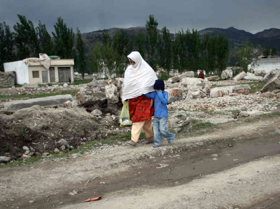 Pakistanis walk past the rubble of bin Laden's demolished compound this week.