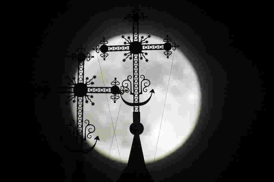 The full moon rises behind a steeple with crosses of an Orthodox church in the town of Novogrudok, Belarus. 