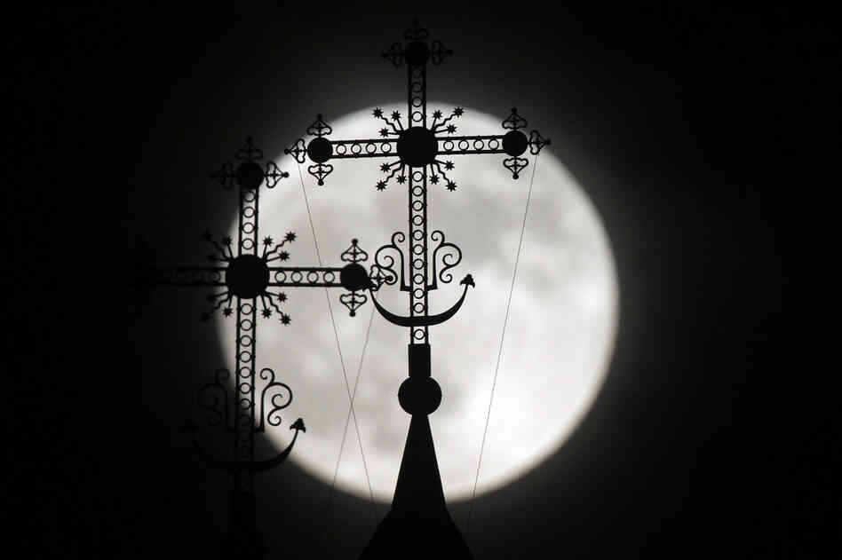 The full moon rises behind a steeple with crosses of an Orthodox church in the town of Novogrudok, Belarus. 