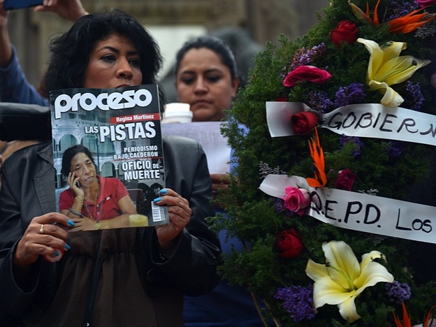 A mourner holds up a copy of Proceso magazine with investigative reporter Regina Martinez on its cover at the vigil in Mexico City last week. At the end of April, Martinez's body was found in her bathroom, beaten and strangled.