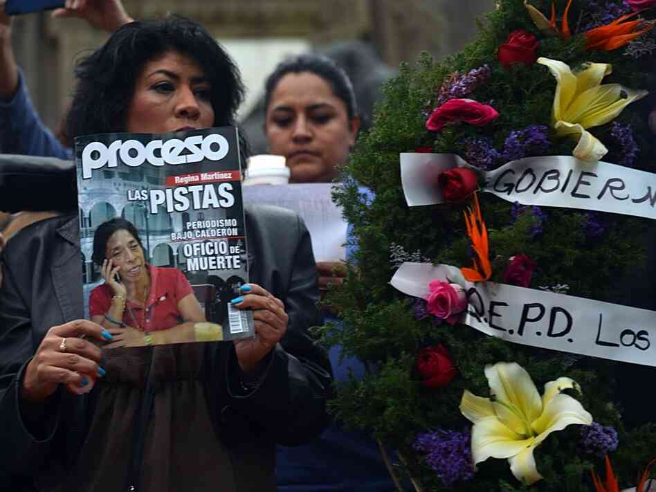 A mourner holds up a copy of Proceso magazine with investigative reporter Regina Martinez on its cover at the vigil in Mexico City last week. At the end of April, Martinez's body was found in her bathroom, beaten and strangled.