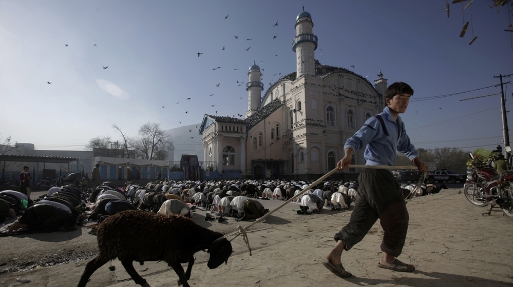 The Afghan government wants Muslim preachers to tone down sermons that often criticize the presence of American troops and praise the Taliban. Here, an Afghan youth drags his sheep past a group of men praying at a mosque in Kabul in November 2011.