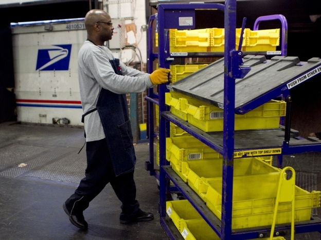 An employee loads flat trays onto a truck at the U.S. Postal Service processing and distribution center in Merrifield, Va. The USPS, which is projecting a $14.1 billion loss this fiscal year, is discussing restructuring options with potential advisers.