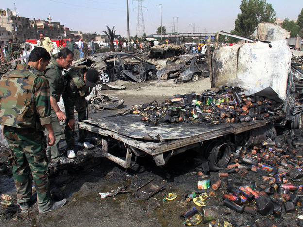 Syrian soldiers check a burned truck in front of a damaged military intelligence building where two bombs exploded, at Qazaz neighborhood in the Syrian capital, Damascus, on Thursday.