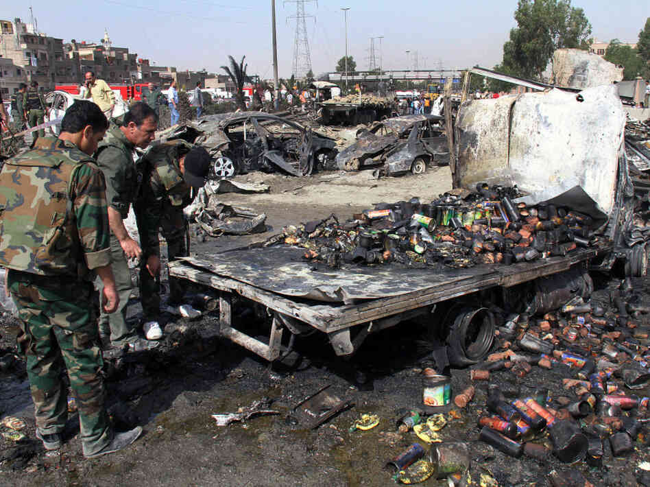 Syrian soldiers check a burned truck in front of a damaged military intelligence building where two bombs exploded, at Qazaz neighborhood in the Syrian capital, Damascus, on Thursday.