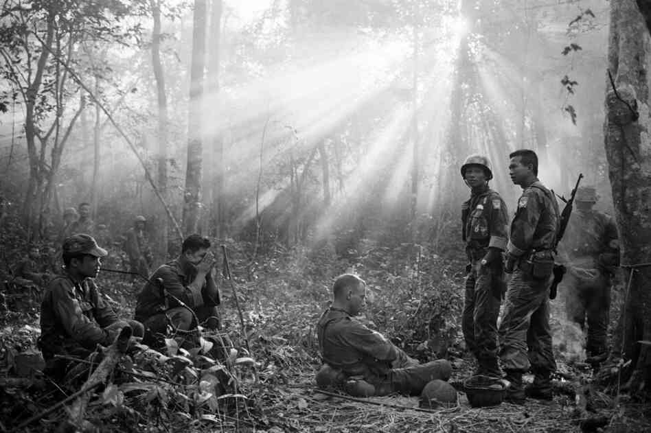 The sun breaks through dense jungle foliage as South Vietnamese troops, joined by U.S. advisers, rest after a cold, damp and tense night of waiting in an ambush position for a Viet Cong attack that didn't come, January 1965.