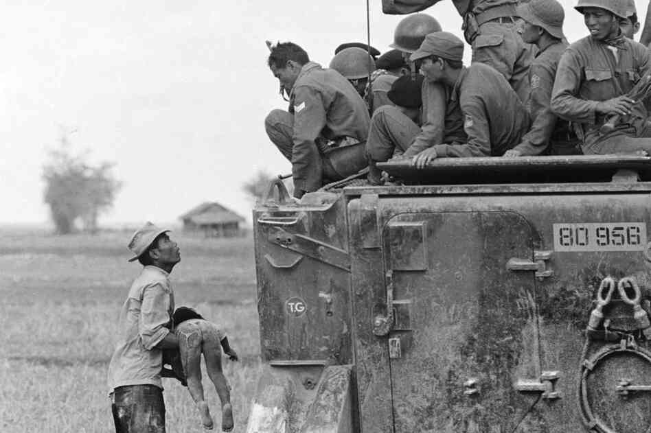 A father holds the body of his child as South Vietnamese Army Rangers look down from an armored vehicle, March 1964. The child was killed as government forces pursued guerrillas into a village near the Cambodian border. This is one of several photos that earned Faas the first of two Pulitzer Prizes.